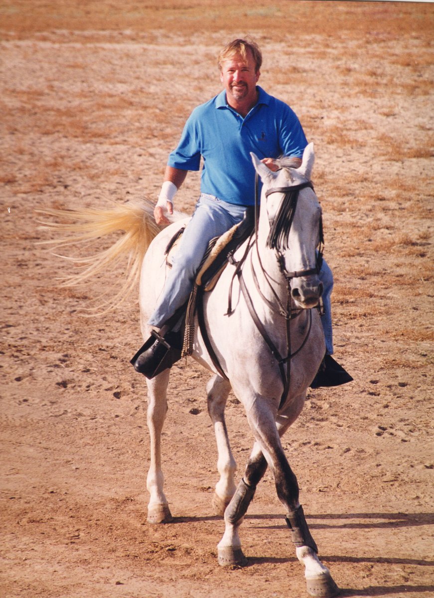 On a white horse.